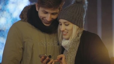 Genç çift smartphone cep telefonu ile fotoğraf geceleri bir şehirde sokak izliyor..