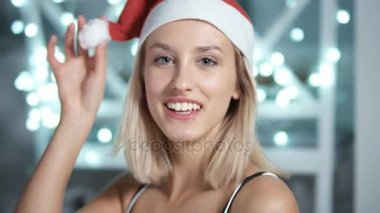 Arka plan parlayan üzerinde santa claus şapka oynak çekici genç kadın portresi.