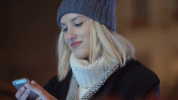 Young woman using mobile phone in a city at night. — Stock Video