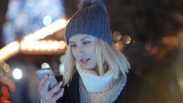 Jonge vrouw met behulp van mobiele telefoon in een stad bij nacht. — Stockvideo