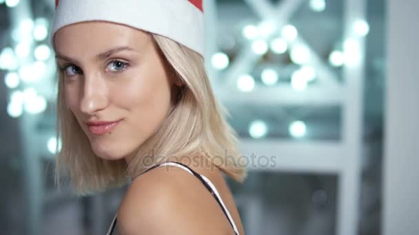 Retrato de joven atractiva juguetona en sombrero de santa claus sobre fondo brillante . — Vídeos de Stock