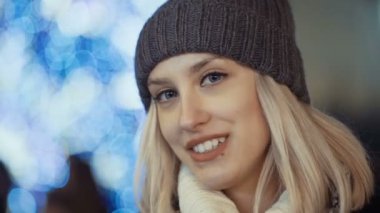 Bir şehirde Noel pazarında genç gülümseyen kadın.