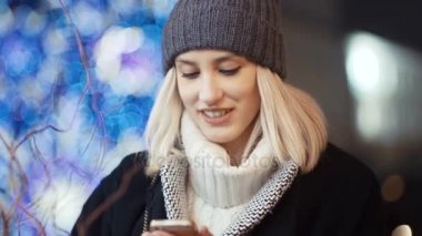 Cep telefonuyla bir şehirde gece genç kadın.