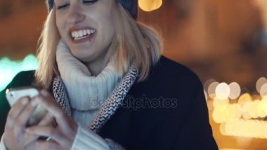 Cep telefonuyla bir şehirde gece genç kadın.