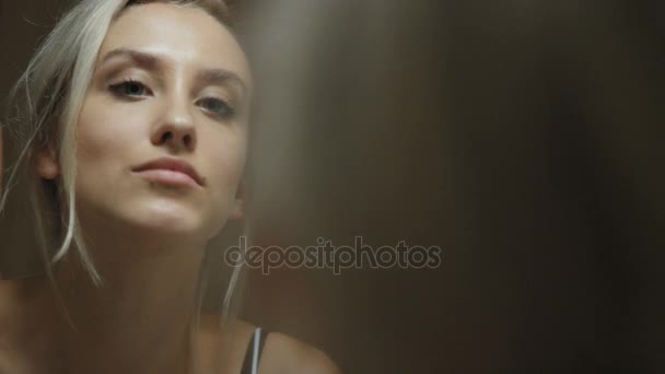 Mujer joven mirando su cara en el espejo del baño en casa . — Vídeo de stock