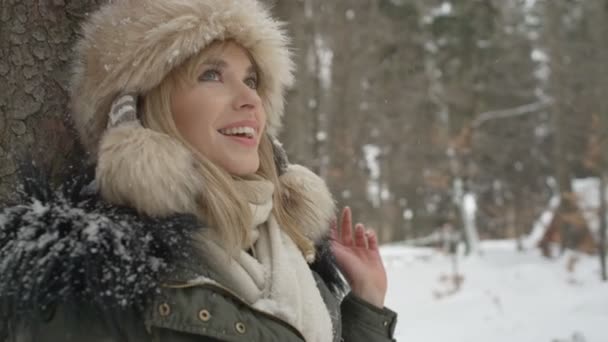 Retrato de una mujer sonriente disfrutando del invierno en un bosque . — Vídeos de Stock