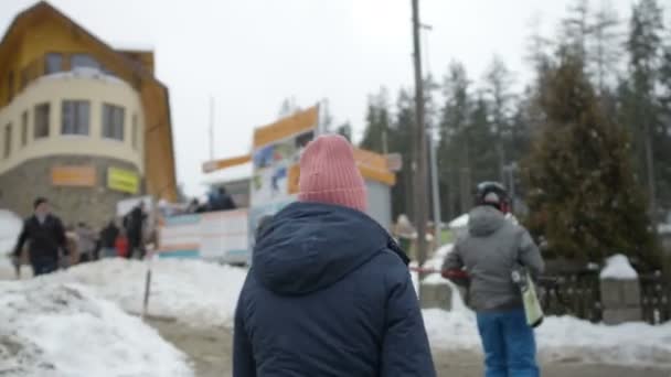 Jonge lachende vrouw in winter kleding lopen in de buurt van de skilift. — Stockvideo