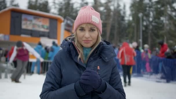 Young smiling woman in winter clothing waiting for her friends near ski lift. — Stock Video