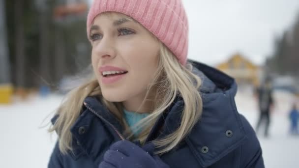 Jovem mulher sorridente em roupas de inverno esperando por seus amigos perto de teleférico de esqui . — Vídeo de Stock