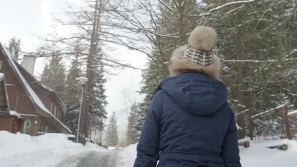 Jonge vrouw lopen in een winter bos weg en genieten van uitzicht. — Stockvideo