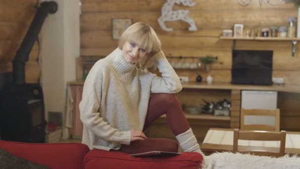 Hermosa chica con suéter usando una tableta en casa en invierno . — Vídeos de Stock