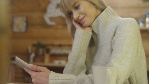 Όμορφη κοπέλα φορώντας πουλόβερ χρησιμοποιώντας ένα tablet στο σπίτι το χειμώνα. — Αρχείο Βίντεο