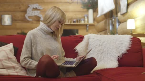 Beautiful girl wearing sweater using computer at home in winter. — Stock Video