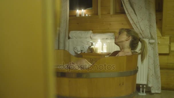 Молода жінка приймає ванну в дерев'яній ванні . — стокове відео
