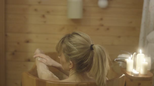 Jeune femme prenant un bain dans une baignoire en bois . — Video