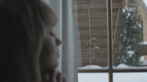 Νεαρή γυναίκα συλλογισμένος αναζητούν μέσα από ένα παράθυρο. — Αρχείο Βίντεο