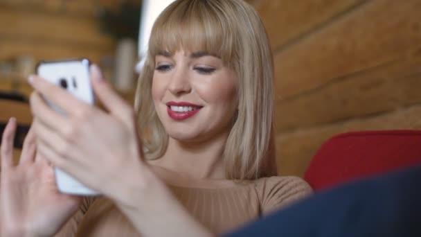 Молода красива блондинка використовує телефон вдома . — стокове відео