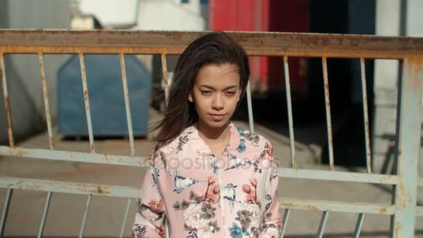 Νεαρή όμορφη γυναίκα που φοράει σακάκι βομβαρδιστικό ποζάρει πάνω από μεταλλικό φράκτη. — Αρχείο Βίντεο