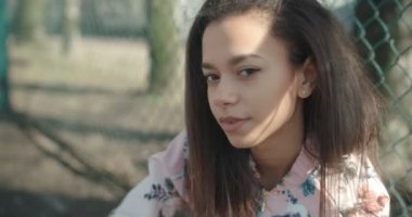 Metal çitin üzerinden poz bombardıman ceket giyen genç güzel kadın.