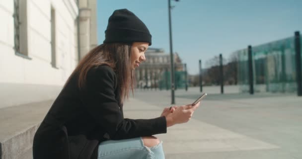 Retrato de una joven afroamericana usando teléfono, al aire libre . — Vídeos de Stock