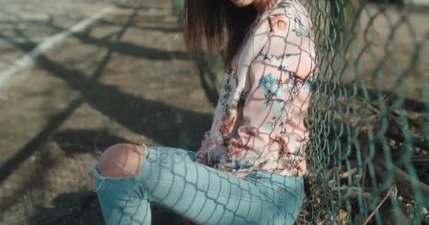 Jovem mulher bonita vestindo jaqueta bomber posando sobre cerca de metal . — Vídeo de Stock