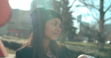 Bir bankta oturan genç güzel Afrikalı-Amerikalı kadın.