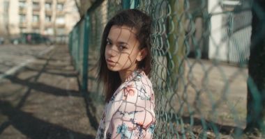 Metal çitin üzerinden poz bombardıman ceket giyen genç güzel kadın.