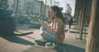 Güzel genç kadın telefonla güneşli gün boyunca yazarak.