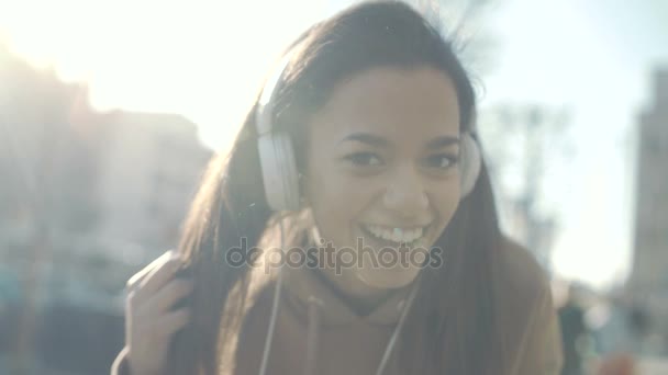 Jonge vrouw met hoofdtelefoon genieten van tijd in een stad. — Stockvideo