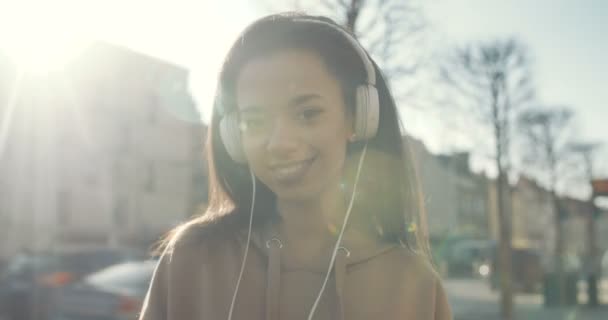 Mujer joven con auriculares disfrutando del tiempo en una ciudad . — Vídeo de stock