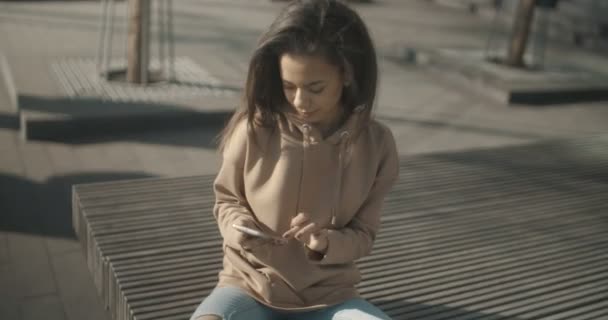 Mooie jonge vrouw te typen op de telefoon tijdens zonnige dag. — Stockvideo
