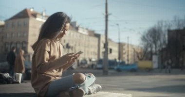 Güzel genç kadın telefonla güneşli gün boyunca yazarak.