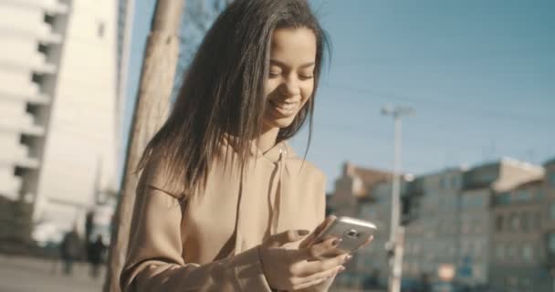 Mooie jonge vrouw te typen op de telefoon tijdens zonnige dag. — Stockvideo