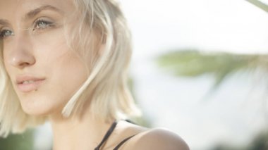 Genç güzel sarışın kız tropik sahilde poz.