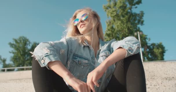 Mujer joven con auriculares disfrutando del tiempo en una ciudad . — Vídeos de Stock