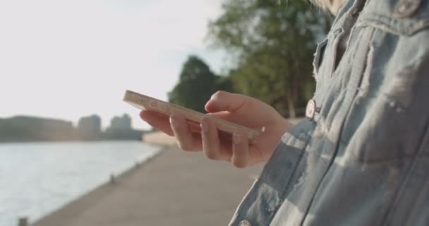 Gros plan de jeunes mains féminines utilisant le téléphone, à l'extérieur . — Video