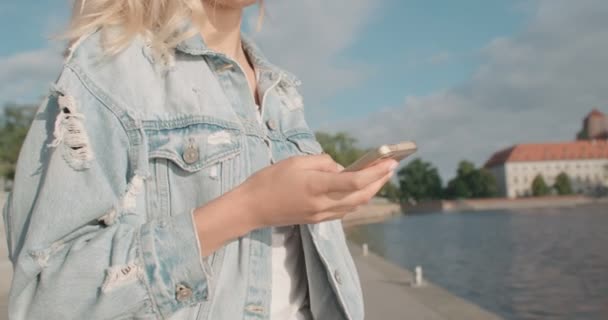 Mujer rubia joven usando el teléfono en una ciudad . — Vídeos de Stock