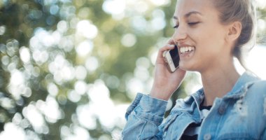 Telefon bir şehirde kullanan genç sarışın kadın.