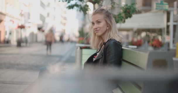 Όμορφη γυναίκα κάθεται σε παγκάκι και περιμένει για μια ημερομηνία. — Αρχείο Βίντεο