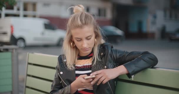 Joven mujer caucásica usando el teléfono en una ciudad . — Vídeos de Stock