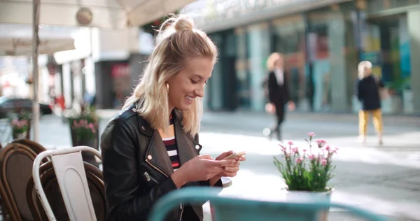 Jeune femme caucasienne utilisant le téléphone dans un café de la ville . — Photo