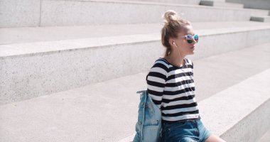 Genç kadın bir şehirde vaktinizi kulaklıklar ile.