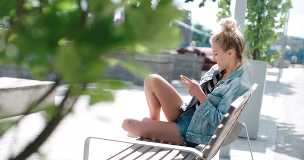 Bastante chica caucásica usando el teléfono en un parque de la ciudad . —  Fotos de Stock