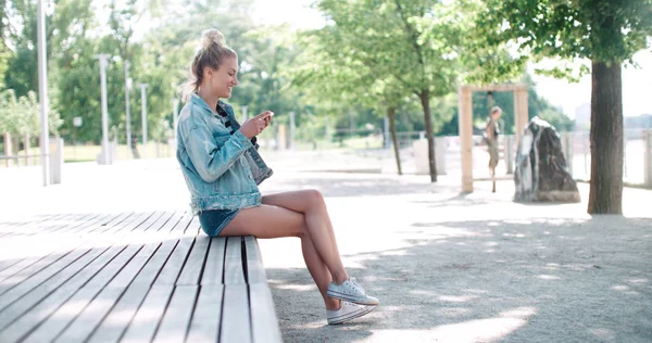 Jolie fille caucasienne utilisant le téléphone dans un parc de la ville . — Photo