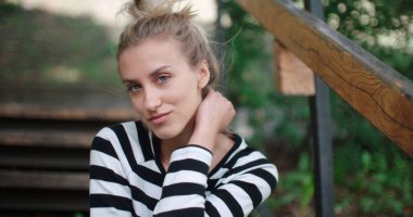 Bir kameraya bakarak ve gülümseyen güzel sarışın kız.