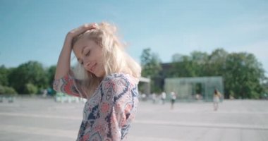 Kameraya bakarak ve açık havada gülümseyen genç kadın.