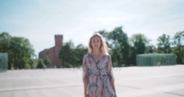 Kameraya bakarak ve açık havada gülümseyen genç kadın.