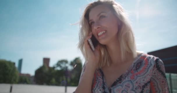 Mooie jonge vrouw op telefoon te praten tijdens een zonnige dag. — Stockvideo