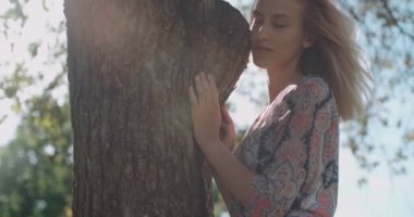 Genç doğal güzel kadın rahatlatıcı bir güneşli parkta. 