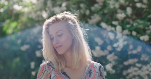 Jovem mulher naturalmente bonita relaxando em um parque ensolarado . — Vídeo de Stock